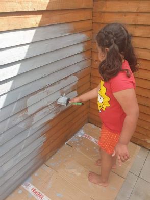 Nola helping Mum and Oisin paint the fence.